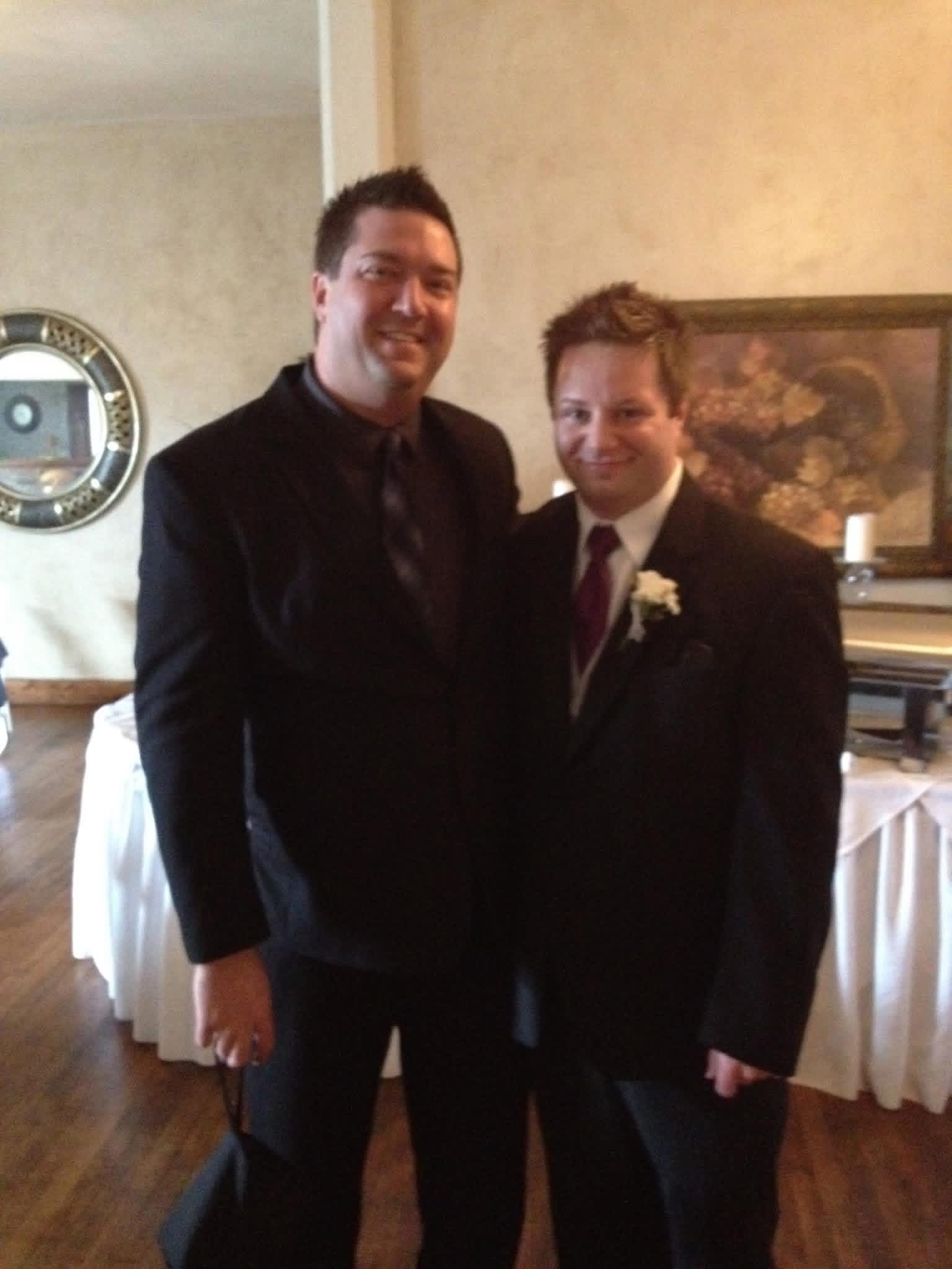Shane (left) dressed up in a suit and tie with a friend at a wedding.