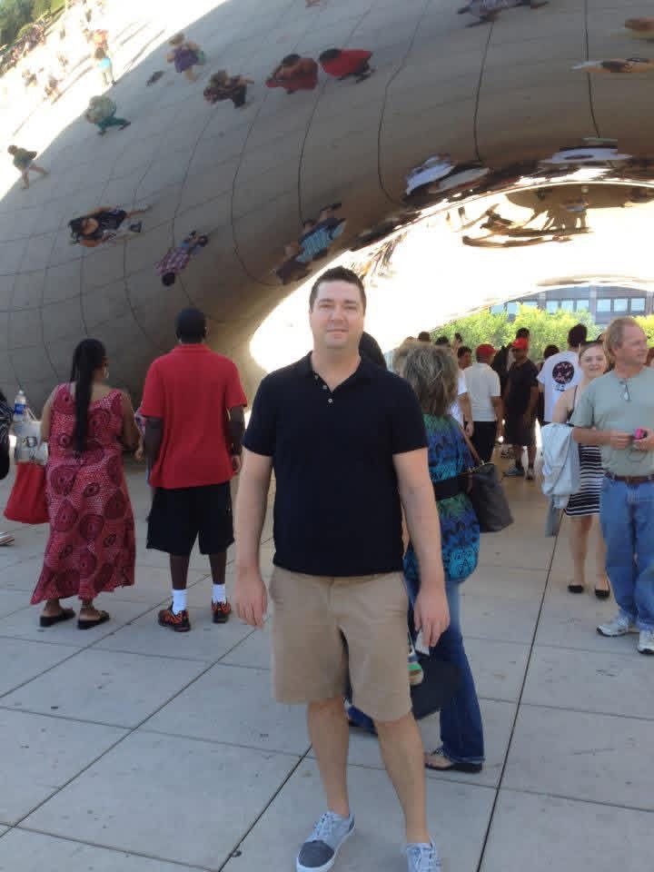 Shane standing at Cloud Gate — "the Bean" — in Chicago's Millennium Park.