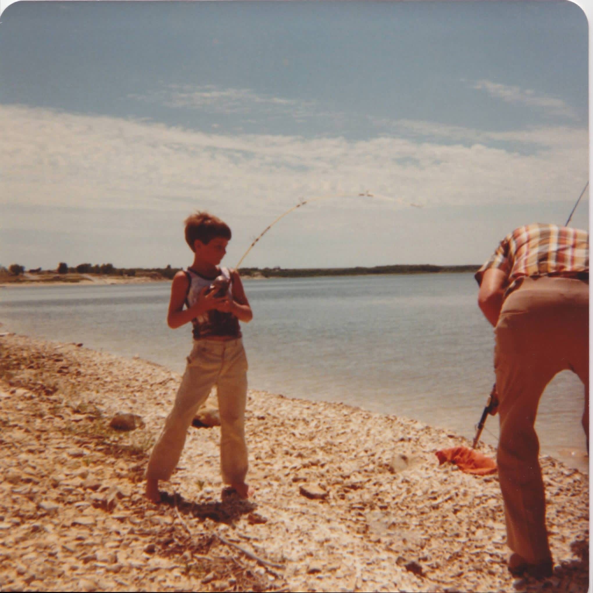Shane as a boy, fishing at the lakeshore with his grandpa Leo on a summer day.