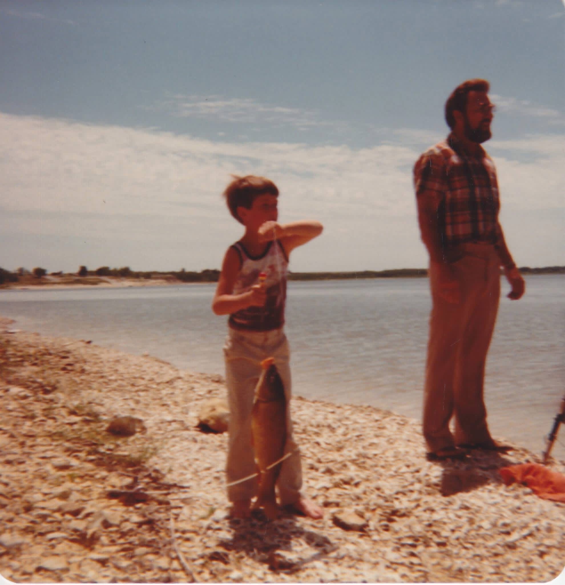 Shane as a boy, proudly holding up a fish he caught, his grandpa Leo standing nearby.