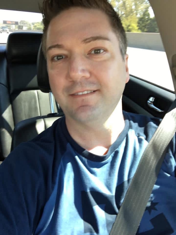 Shane smiling for a selfie in the car on a sunny day.