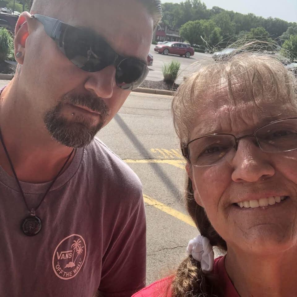 Shane and his mother, Michele, taking a selfie outdoors on a sunny day.
